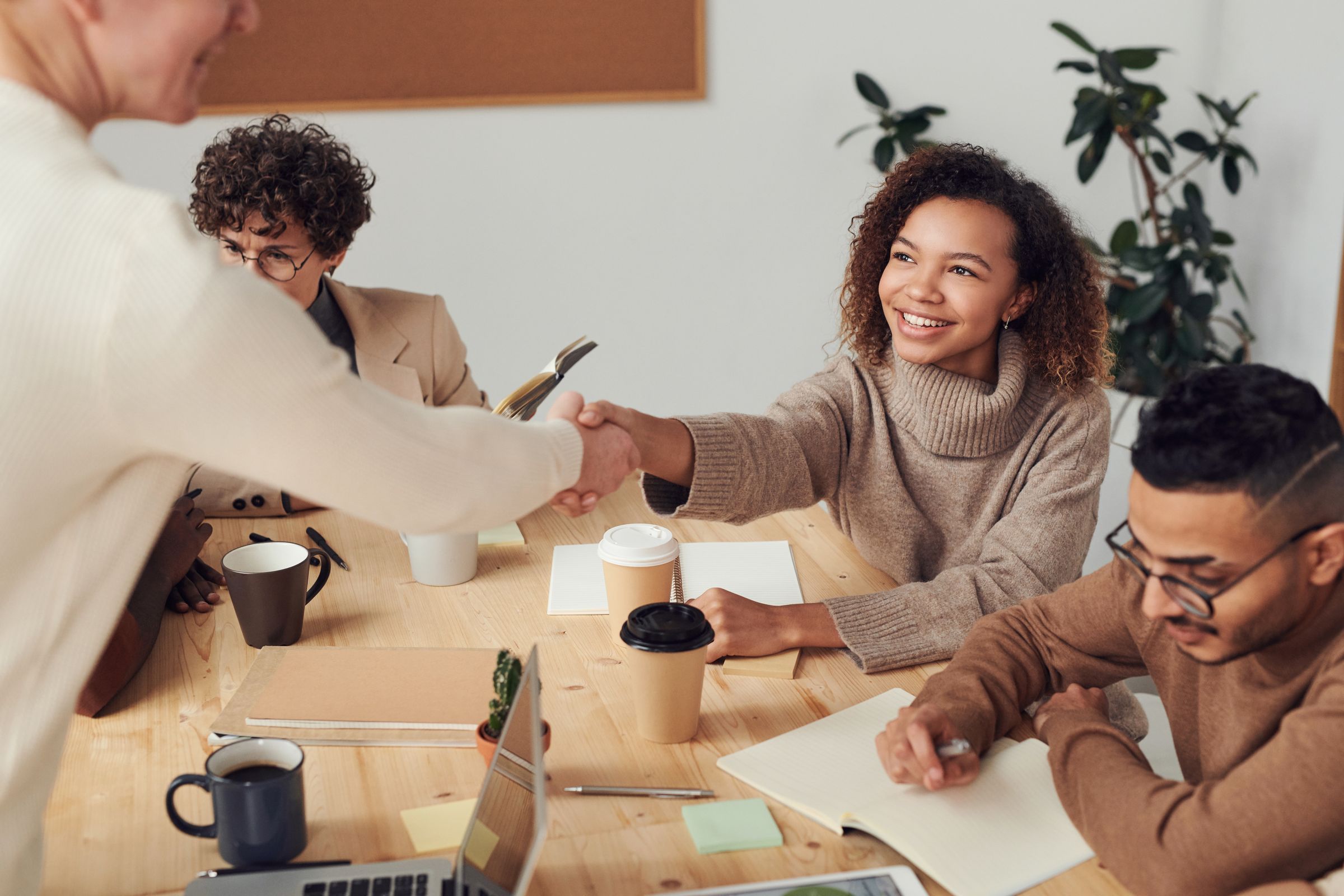 Colleagues smiling and shaking hands during a warm, collaborative meeting